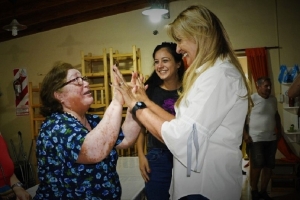 Fassi junto a una abuela y de fondo Ayelen Rasquetti, nueva titular de Desarrollo Social. 