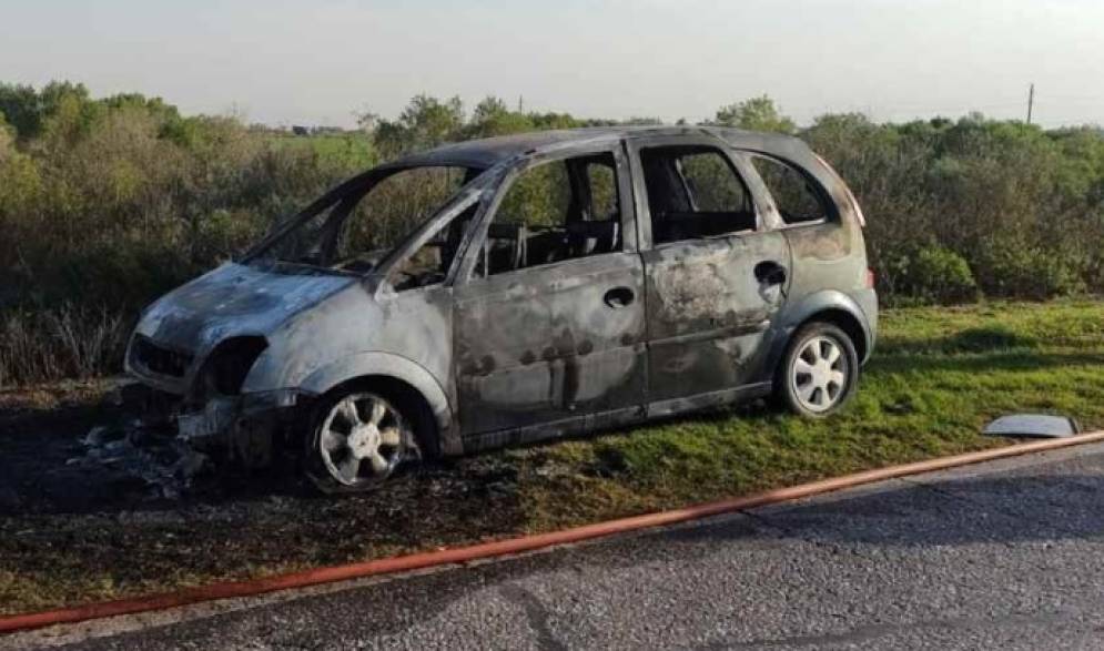 Un coche quemado en la banquina.